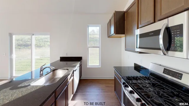 a kitchen with stainless steel appliances a stove microwave and sink