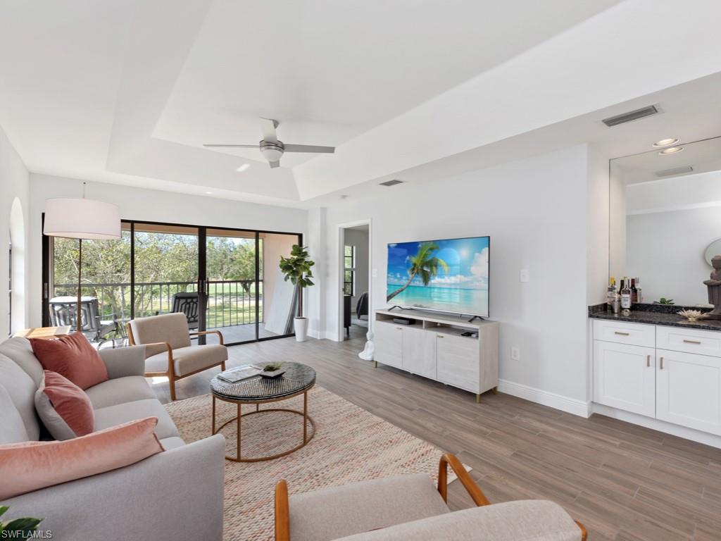 709 Augusta Boulevard, Unit 7095 Naples, FL 34113 - Photo 2 of 16 Living room with ceiling fan, a raised ceiling, and light wood-type flooring