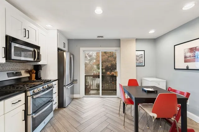 a kitchen that has a table chairs refrigerator and a stove top oven