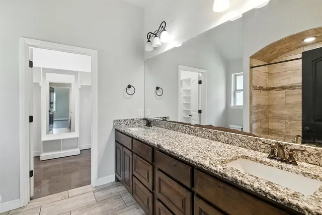 a bathroom with a granite countertop double vanity sink and a mirror