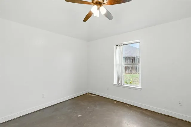 an empty room with a window and a fan