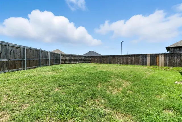 a view of a backyard with a garden and wooden fence
