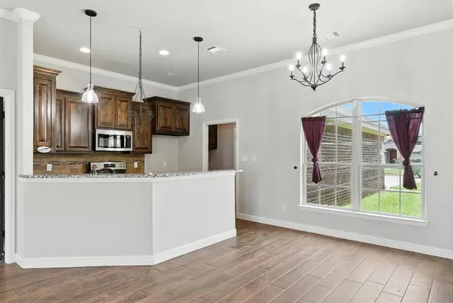 a view of kitchen with granite countertop stainless steel appliances sink and wooden floor