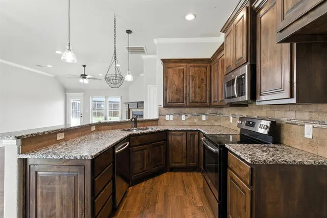 a kitchen with stainless steel appliances granite countertop a sink a stove and a wooden cabinets