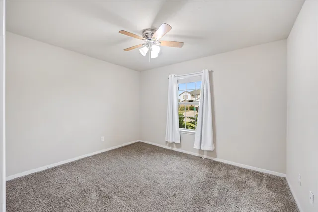 an empty room with windows and chandelier fan