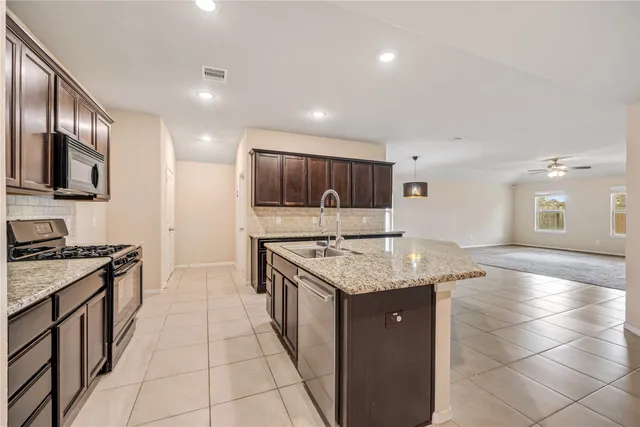 a kitchen with stainless steel appliances granite countertop a stove a sink and a refrigerator