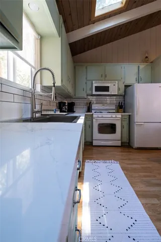 a kitchen with granite countertop a stove a sink and a refrigerator