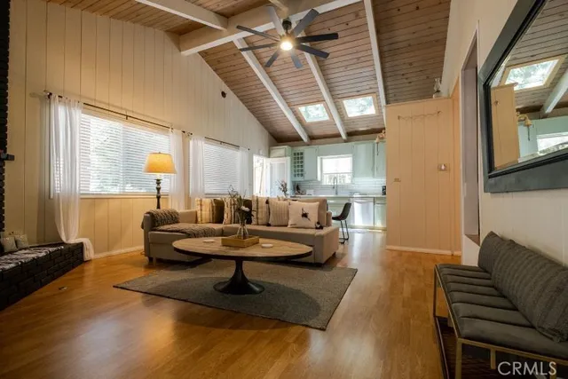 a living room with couches and a flat screen tv with kitchen view