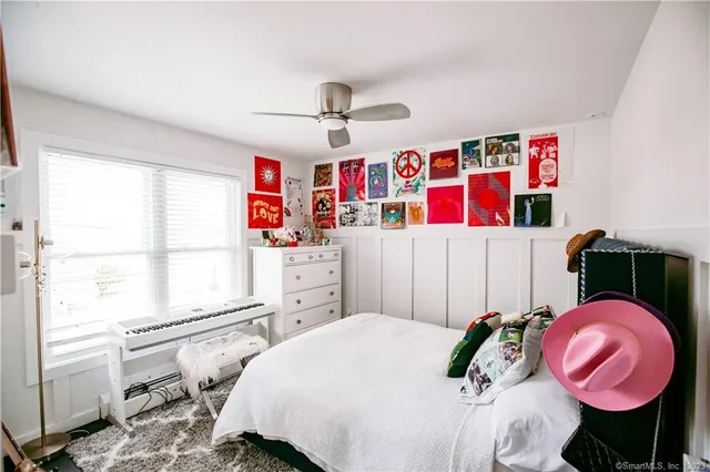 a bedroom with a bed a dresser and a large window