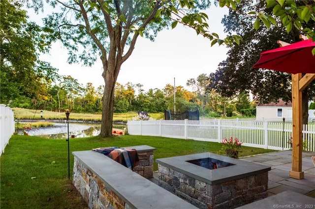 a view of a backyard with couches plants and large trees