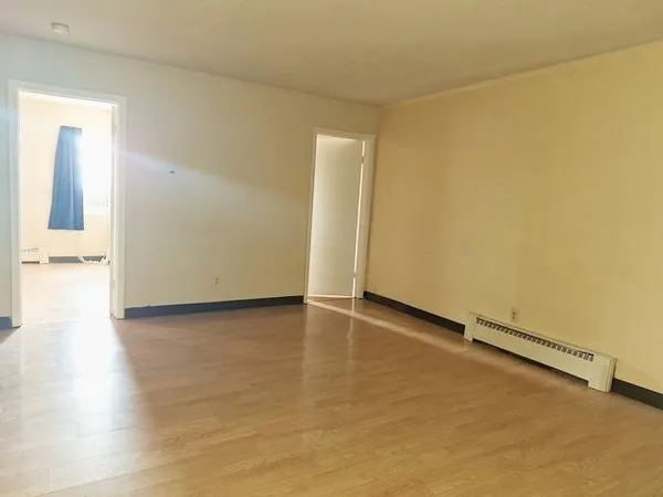 a view of empty room with wooden floor and closet