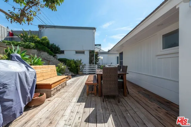 a view of a roof deck with table and chairs a barbeque with wooden floor and fence