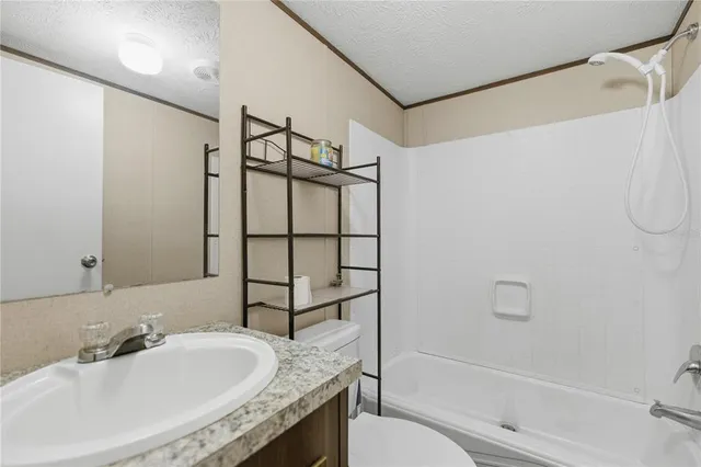 a bathroom with a granite countertop sink a toilet and shower