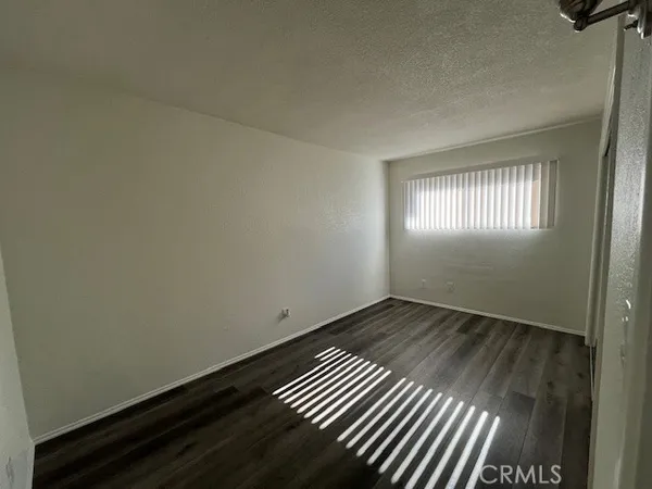 an empty room with wooden floor cabinet and windows