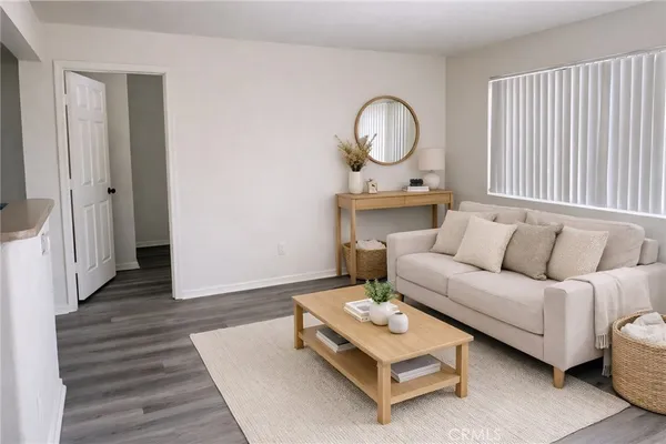 a living room with furniture a wooden floor and next to a window