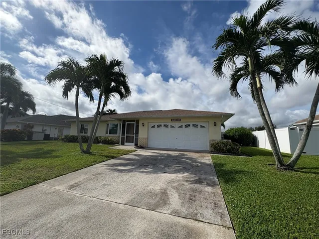 a view of a house with a yard and palm trees