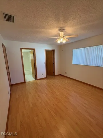 a view of an empty room with chandelier fan and a window