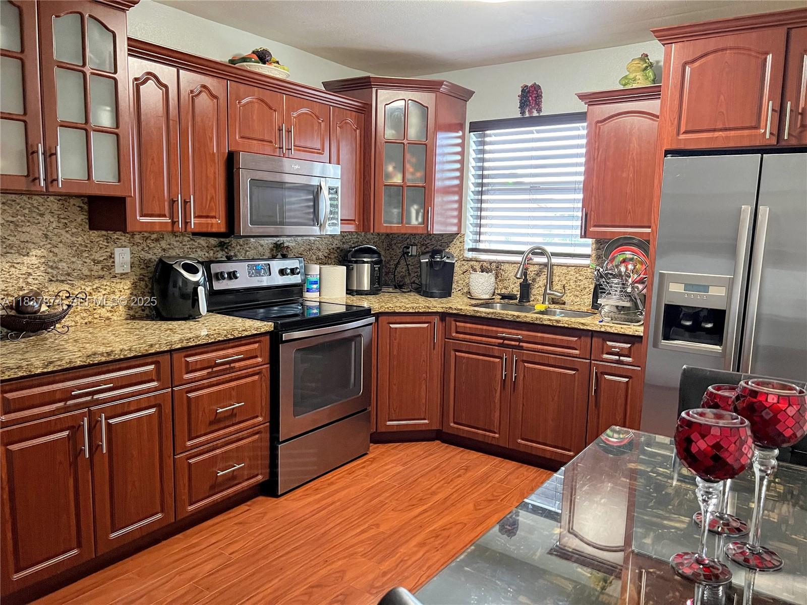 12554 Southwest 211th Terrace Miami, FL 33177 - Photo 23 of 30 a kitchen with stainless steel appliances granite countertop wooden cabinets a stove top oven a sink and dishwasher