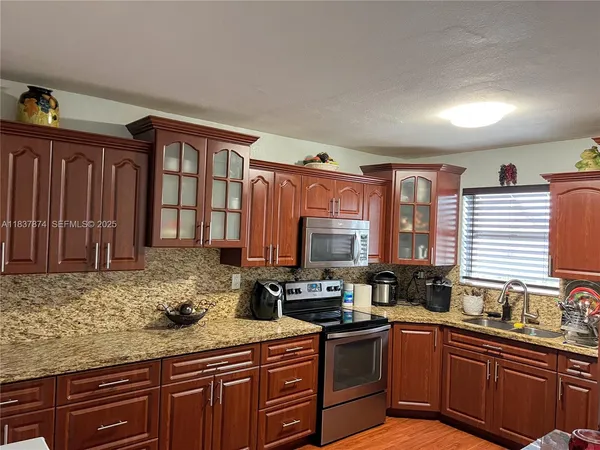 a kitchen with granite countertop a sink stove and cabinets