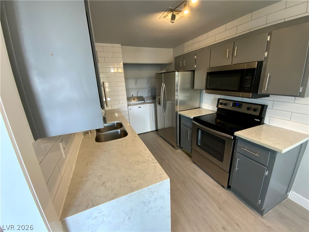466 East Sunset Road, Unit C Henderson, NV 89011 - Photo 3 of 12 Kitchen featuring backsplash, gray cabinets, stainless steel appliances, and a sink