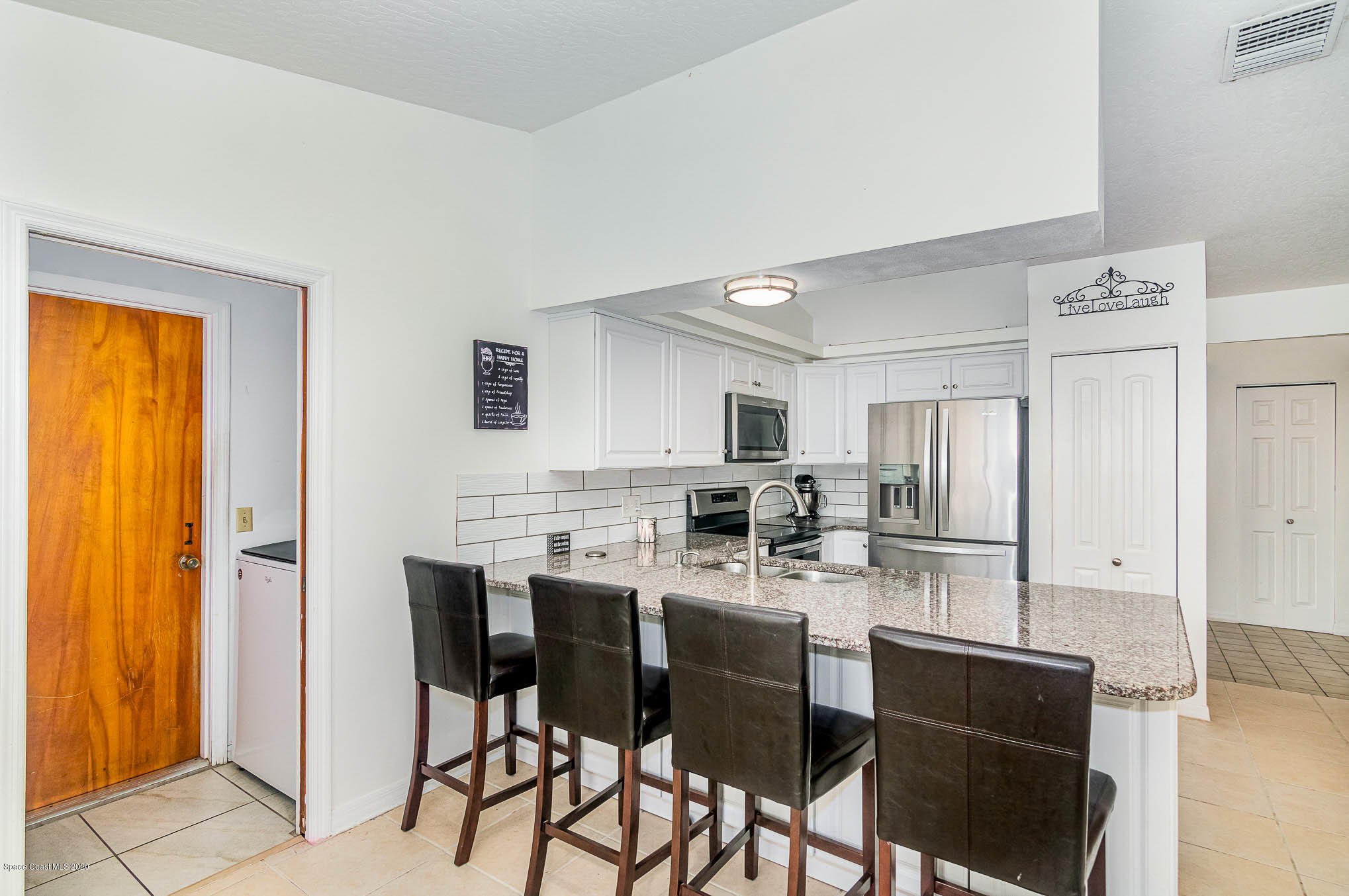 484 Rheine Road Northwest Palm Bay, FL 32907 - Photo 11 of 24 a kitchen with stainless steel appliances kitchen island granite countertop a table chairs and a refrigerator