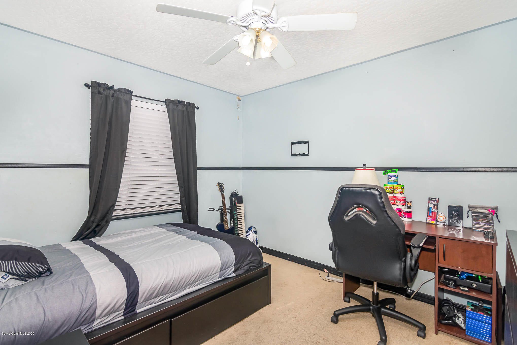484 Rheine Road Northwest Palm Bay, FL 32907 - Photo 16 of 24 a bedroom with a bed a desk and a chandelier