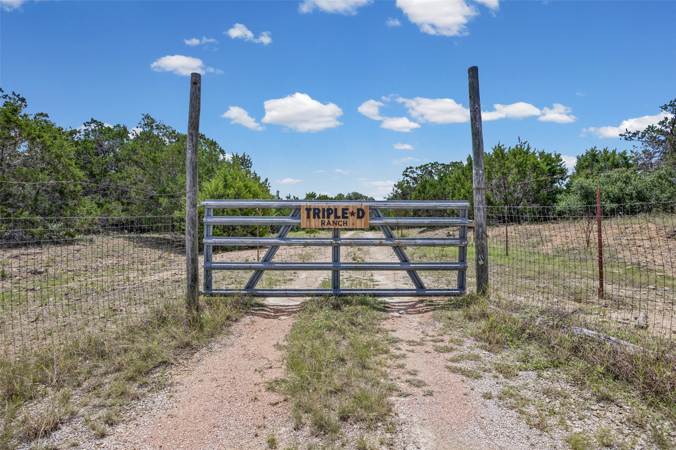 Tbd Cottonwood Road Wimberley, TX 78676 - Photo 1 of 1 Secure entry to the Triple D Ranch, featuring a robust metal gate framed by natural surroundings.