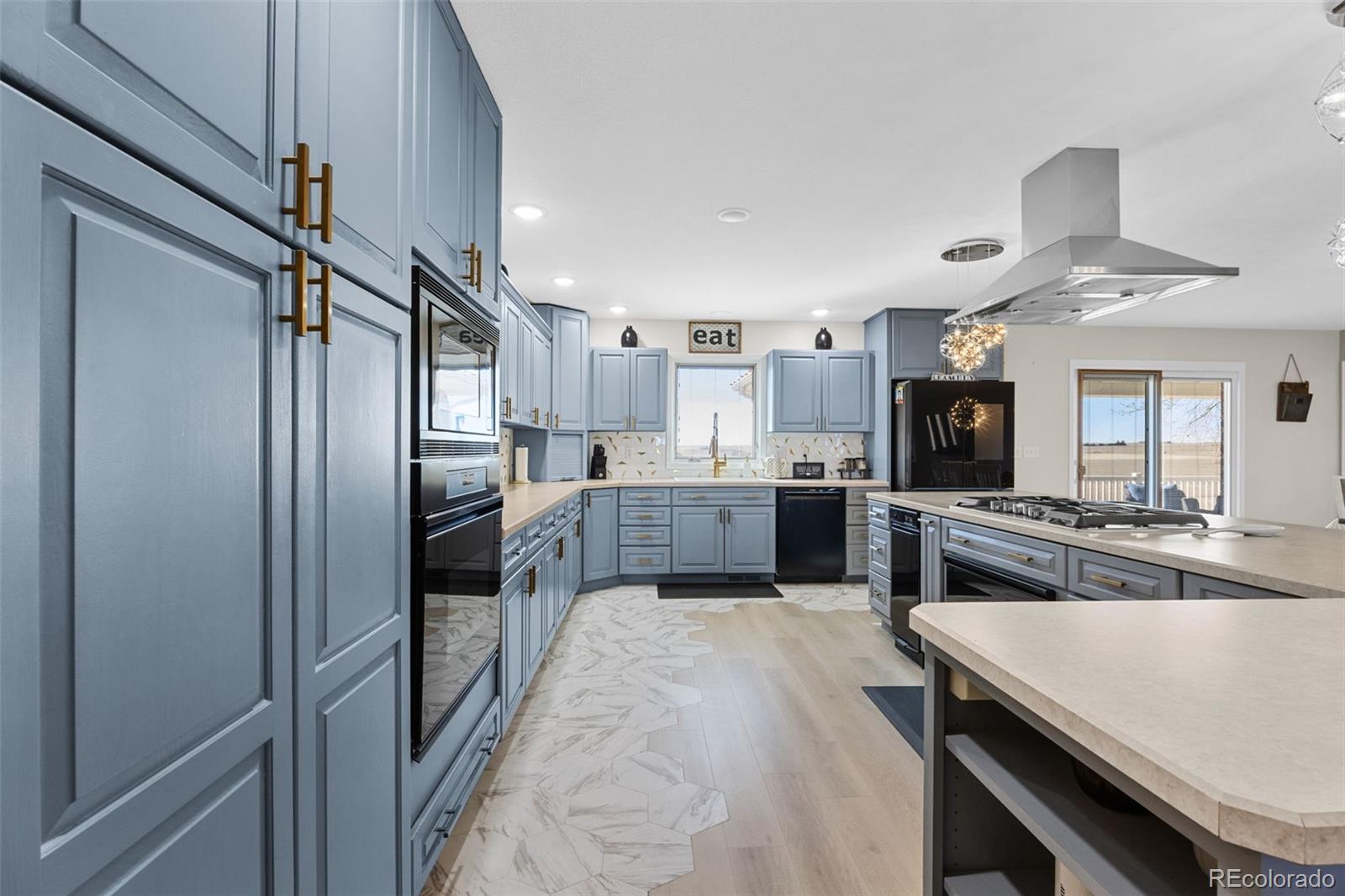 5330 Kiowa-Bennett Road Bennett, CO 80102 - Photo 12 of 50 a kitchen with stainless steel appliances kitchen island granite countertop a refrigerator oven a sink dishwasher and white cabinets with wooden floor