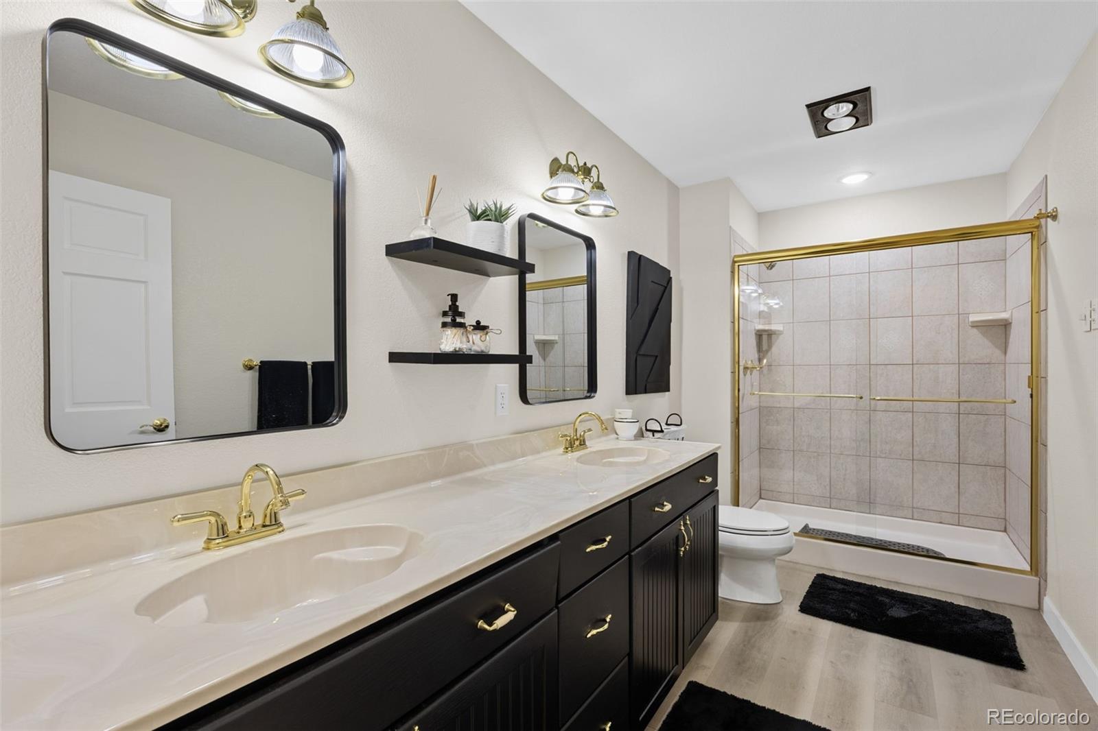 5330 Kiowa-Bennett Road Bennett, CO 80102 - Photo 28 of 50 a bathroom with a double vanity sink a toilet and a mirror