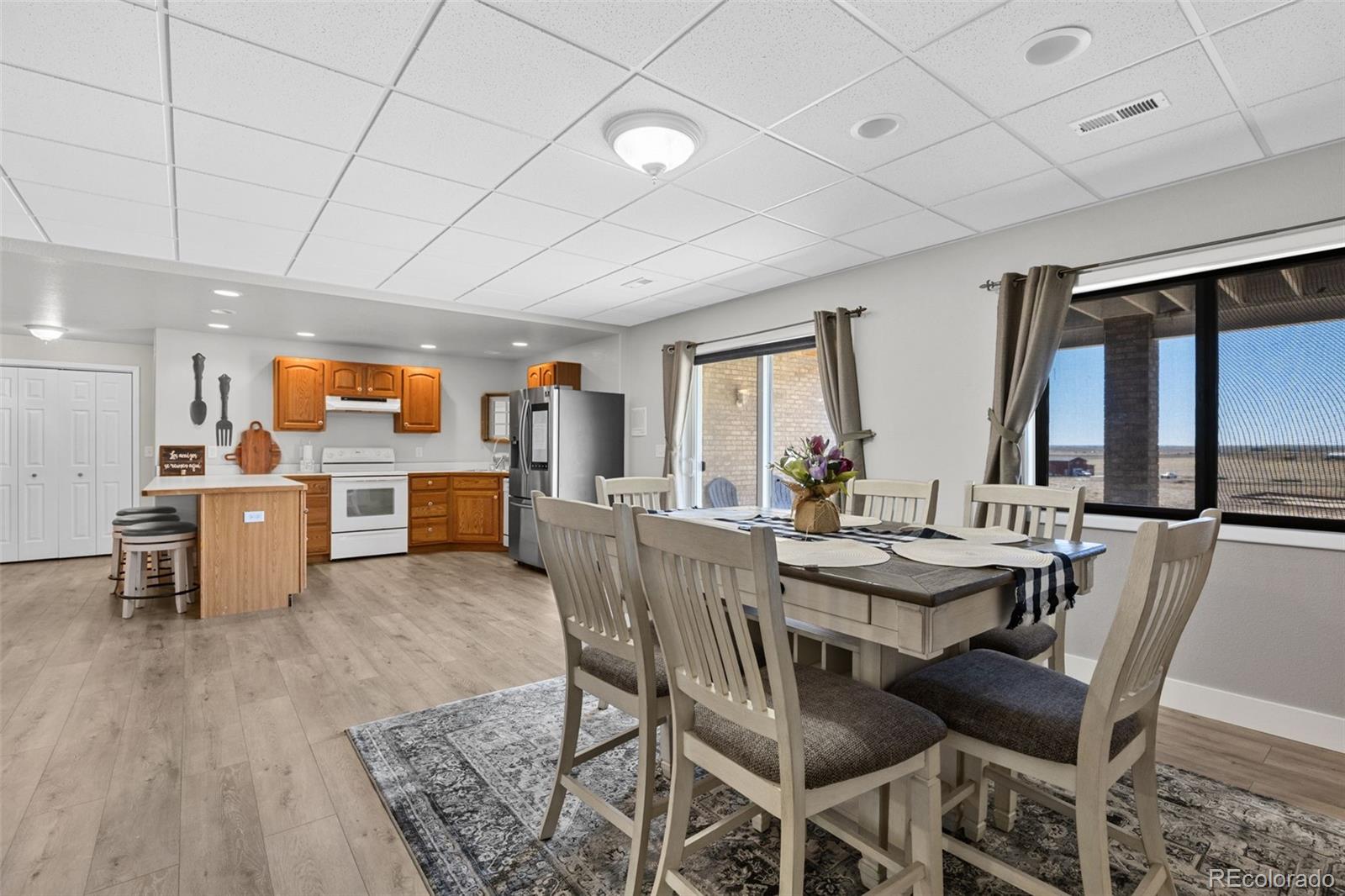 5330 Kiowa-Bennett Road Bennett, CO 80102 - Photo 37 of 50 a dining room with furniture a kitchen a chandelier a wooden table and chairs