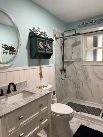 a bathroom with a granite countertop sink a toilet and shower