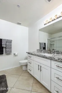 a bathroom with a granite countertop sink a toilet and a mirror