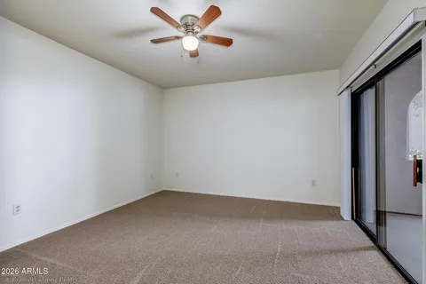 an empty room with chandelier fan and windows