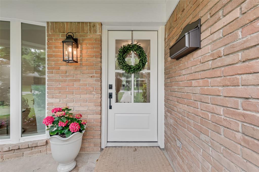 The property features a brick exterior with a white entry door, a dark-colored wall-mounted light fixture, and a dark-colored mailbox
