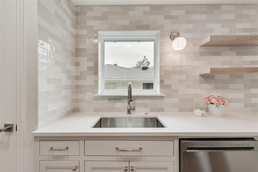 13427 Purple Sage Road Dallas, TX 75240 - Photo 11 of 31 The kitchen features white shaker style cabinetry with metal hardware, a stainless steel sink with a gooseneck faucet, white countertops, and a full tile backsplash