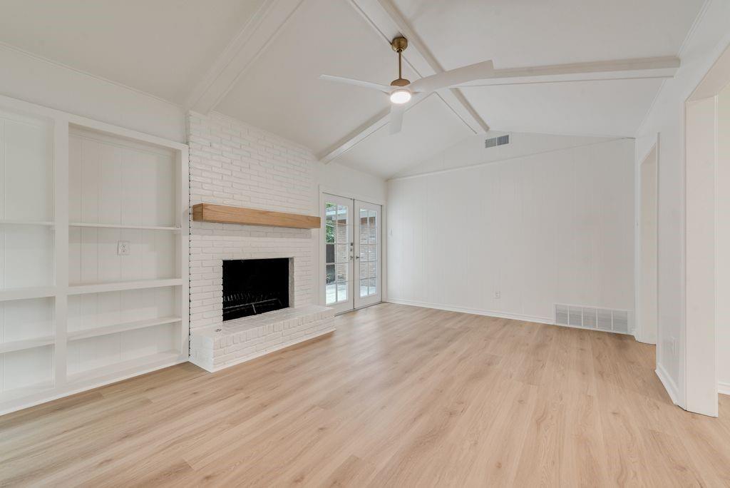 13427 Purple Sage Road Dallas, TX 75240 - Photo 6 of 31 an empty room with wooden floor a ceiling fan a fireplace and windows