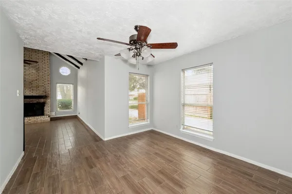 a view of an empty room with a window and wooden floor