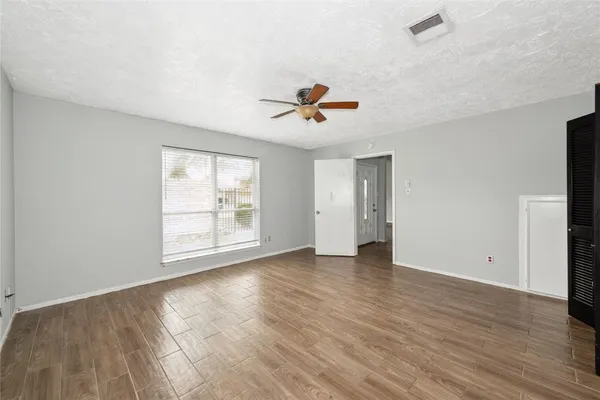 an empty room with wooden floor and windows