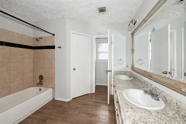 a bathroom with a granite countertop tub sink and mirror