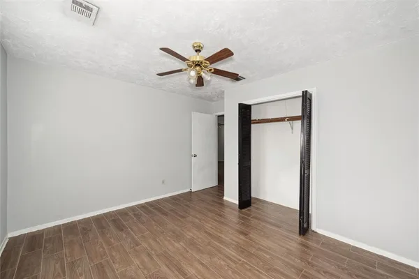 a view of a room with wooden floor and a ceiling fan
