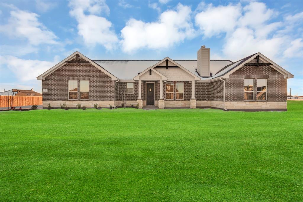 a front view of a house with a yard and large trees