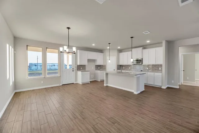 a large kitchen with cabinets wooden floor and stainless steel appliances