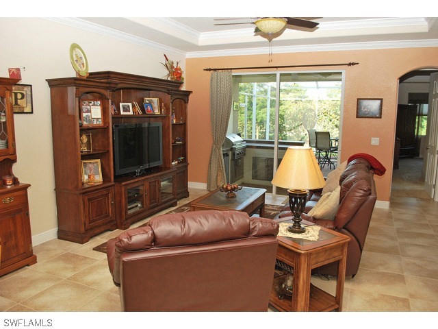19612 Tesoro Way Fort Myers, FL 33967 - Photo 2 of 14 a living room with furniture a flat screen tv and a floor to ceiling window
