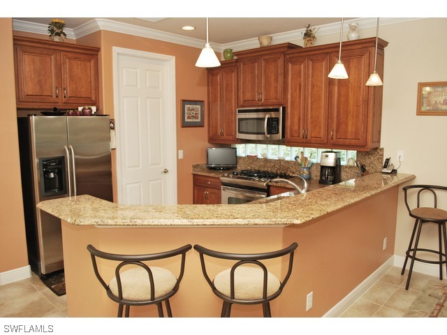 19612 Tesoro Way Fort Myers, FL 33967 - Photo 4 of 14 a kitchen with stainless steel appliances granite countertop a table chairs and granite counter tops