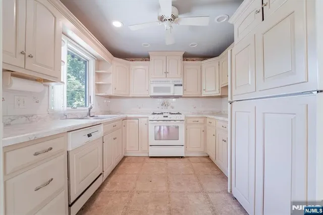 a kitchen with granite countertop white cabinets and white stainless steel appliances
