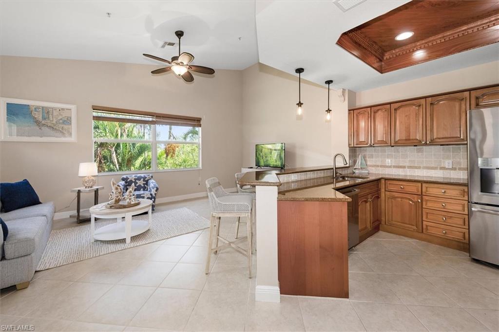 8375 Whisper Trace Way, Unit M203 Naples, FL 34114 - Photo 13 of 36 a kitchen with stainless steel appliances kitchen island granite countertop a sink dishwasher stove and cabinets