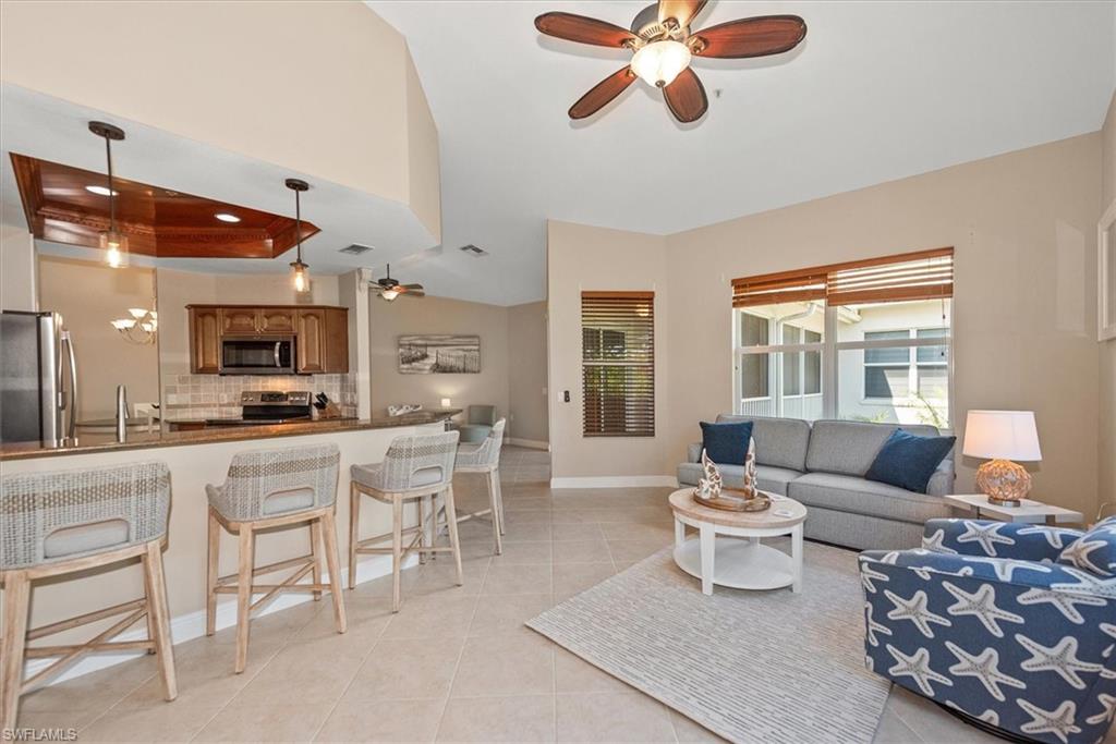 8375 Whisper Trace Way, Unit M203 Naples, FL 34114 - Photo 16 of 36 a living room with furniture a flat screen tv and a large window