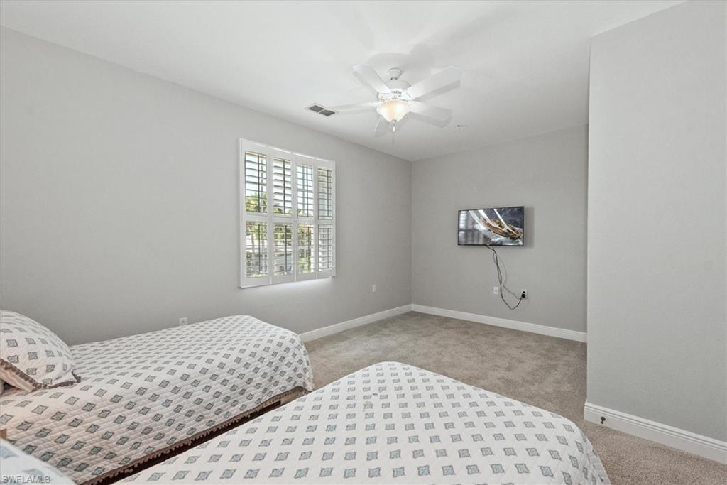 8375 Whisper Trace Way, Unit M203 Naples, FL 34114 - Photo 26 of 36 a bedroom with a large bed and a chandelier