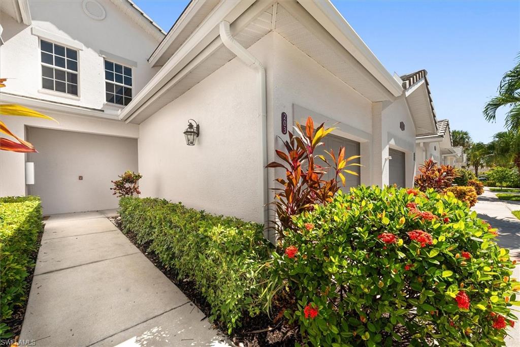 8375 Whisper Trace Way, Unit M203 Naples, FL 34114 - Photo 3 of 36 a front view of a house with lots of flower and flowers