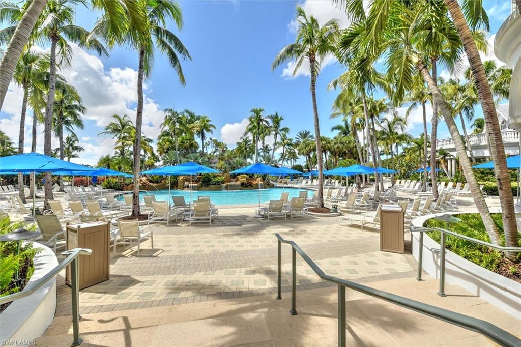 8375 Whisper Trace Way, Unit M203 Naples, FL 34114 - Photo 34 of 36 a view of a swimming pool with a lawn chairs under an umbrella